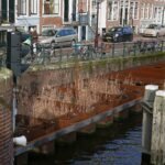 Workers rebuilding a historic brick canal quay wall in Amsterdam