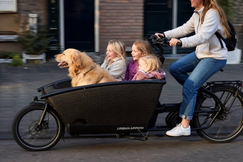 A parent cycling children to school in an Amsterdam cargo bike