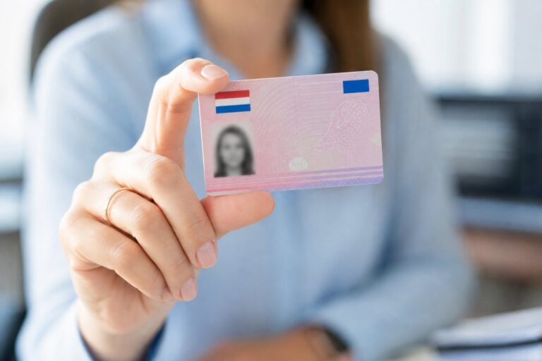 A person holding a Dutch driving license card with a blurred office background.