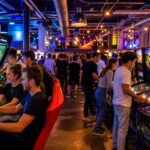 People playing arcade games in a brightly lit gaming center with colorful machines and neon lights.