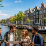 Canal in Amsterdam with traditional narrow buildings, boats on the water, and a group of people exploring the area.