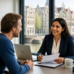 A lawyer and an expat client having a friendly consultation in an office with a view of Amsterdam canals and buildings.