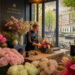 A florist arranging a bouquet inside a flower shop with fresh flowers and a view of Amsterdam canal and buildings outside.