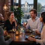 Four business professionals enjoying a relaxed dinner together in a restaurant with views of Amsterdam canals.