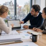 A group of professionals collaborating around a laptop showing a map of Amsterdam in a bright office with city views.
