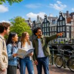 A group of young professionals standing by a canal in Amsterdam with bicycles and traditional houses in the background.