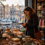 A person choosing last-minute gifts inside a cozy shop with Amsterdam canal houses and bicycles visible through the window.