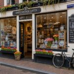 Exterior of a traditional Amsterdam gift shop with large windows displaying various gift items and a bicycle parked outside on a cobblestone street.