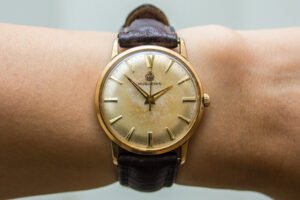 A vintage gold wristwatch with a patinated dial