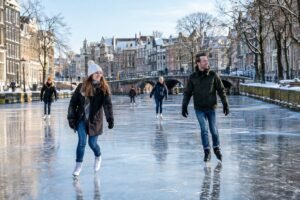 People ice skating on a frozen Amsterdam canal beside historic canal houses.