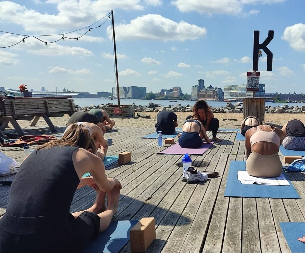 Morning vinyasa flow on the riverside sand at Pllek