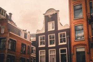 Amsterdam canal house with a neck gable, dormer windows on the roof next door