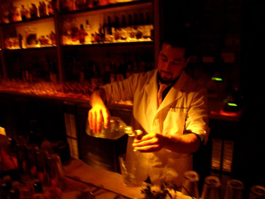 A bartender pouring a cocktail at a bar counter