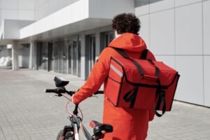 A food delivery rider walking a bicycle with a thermal bag