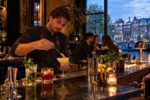 A bartender prepares cocktails while guests relax in a canal-side bar.